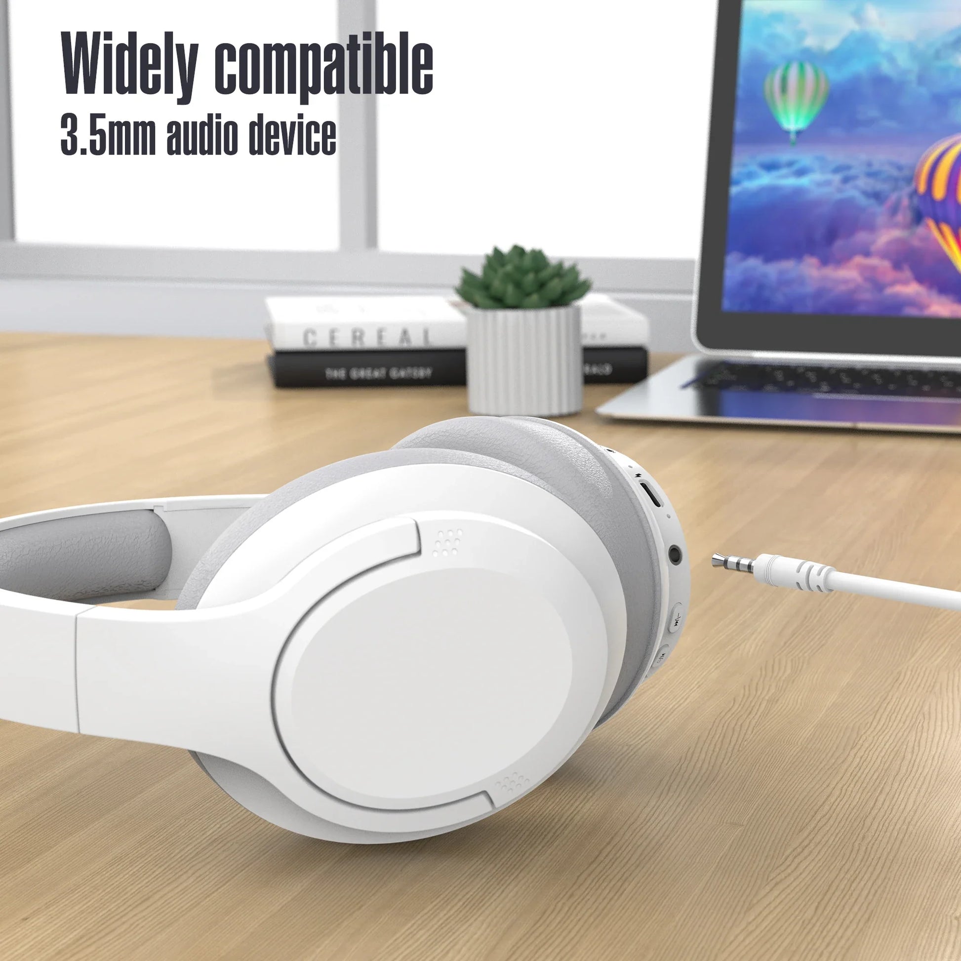 White headphones with a cable on a desk next to a laptop